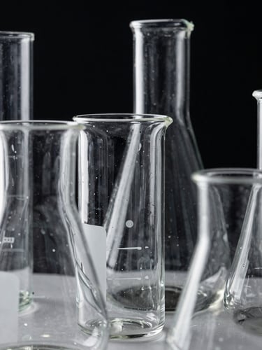 Extreme close-up of high-contrast laboratory glassware, clean reflections, monochrome styling, sharp white studio light highlighting dark borosilicate glass edges against a deep black backdrop.