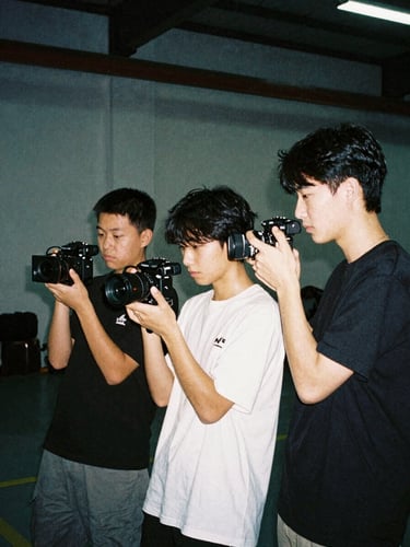 Raw flash photography of young creators filming digital content in an urban warehouse, high-contrast cool tones, 35mm film grain, authentic documentary style