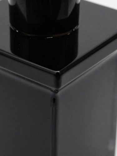 Extreme close-up of a polished black acrylic sculpture with sharp geometric edges, glossy reflections under high-contrast low-key studio light, minimal environment.