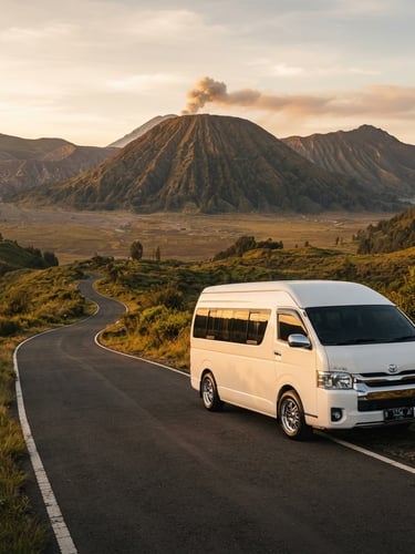 Pristine white Toyota Hiace Premio parked on a scenic mountain road in East Java, golden-hour sunlight reflecting on the clean chassis, majestic Mount Bromo in the far background, 35mm lens