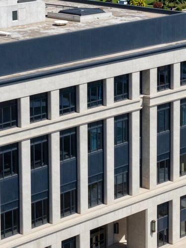 A high-angle architectural shot of a modern federal building exterior with clean geometric lines under bright daylight, crisp navy tones.