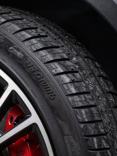 Sleek modern passenger car tire sidewall showing detailed lettering, high-contrast studio lighting, sharp macro detail of rubber compound, 85mm