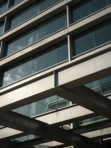 Close-up of structured steel beams and glass facade of a premium corporate headquarters in Muscat, dramatic natural light.