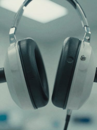 Extreme macro close-up of metallic auditory equipment, sterile clinical photography, cold desaturated teal, flat orthographic framing, 35mm film