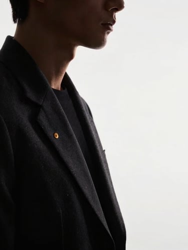 Minimalist studio portrait of a male designer in dark clothing, dramatic side-lighting, soft shadows, clean white background, premium editorial feel.