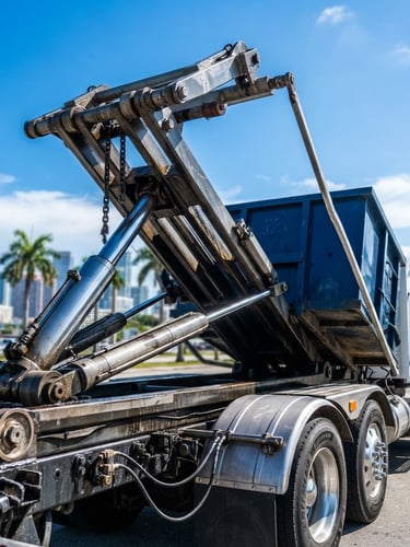 Low-angle heroic shot of a heavy-duty roll-off truck's hydraulic hoist mechanism, clean and branded, under crisp Miami sunlight, sharp focus.