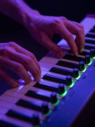 Close-up of hands adjusting dials on an analog synthesizer, neon backlighting, electric violet and green accents.