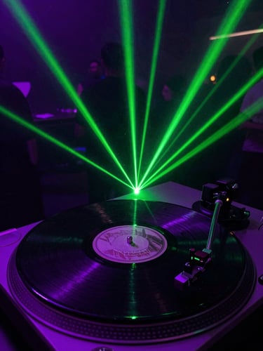 A spinning vinyl record on a turntable under neon green laser beams, dust particles catching the light, gritty club photography.