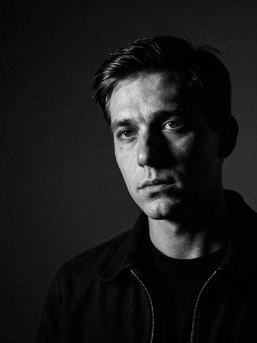 Cinematic high-contrast black and white portrait of a cinematographer, low-key lighting, dramatic shadows, anamorphic lens look, 35mm film grain, negative space on the left.