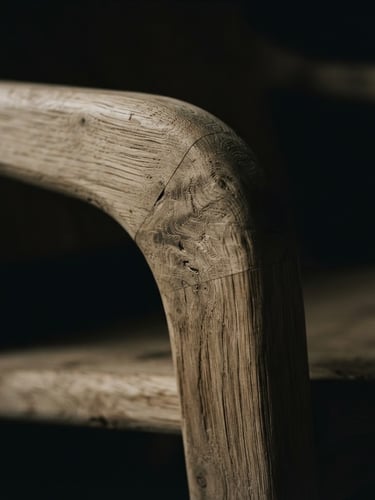 Extreme close-up of a minimalist lounge chair, raw oak grain-matched wood texture, dramatic low-key studio lighting with deep shadows, 35mm lens, cinematic depth of field.