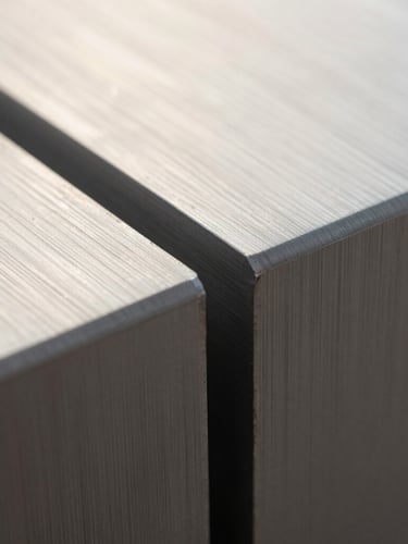 Macro photograph of a milled aluminum seam under soft morning light, showing precise metallic grain and a brushed finish, minimalist composition.