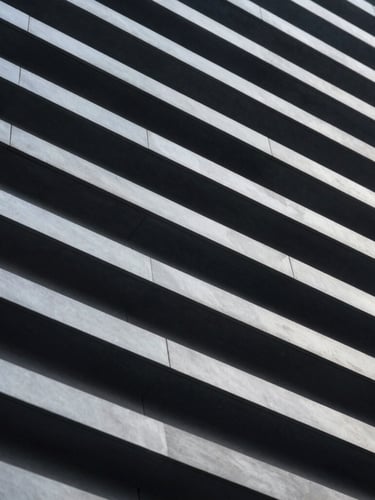 High-contrast macro photograph of a clean, geometric architectural structure with repeating linear patterns, cool-toned lighting, deep slate shadows.