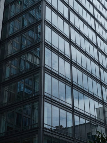 Wide architectural angle of a modern glass facade in São Paulo, cool diffused daylight, deep blue and slate gray tones, editorial corporate photography