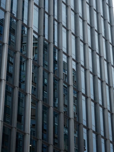 Abstract geometric pattern of glass and steel skyscraper facade, cool diffused daylight, deep blue and slate gray tones, architectural details, 35mm lens.