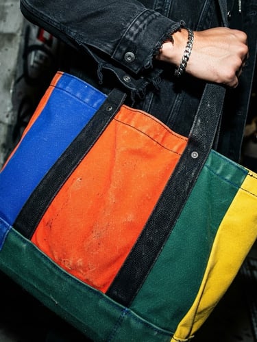 Close-up of heavyweight canvas tote bag texture, vibrant color-blocked design, hard flash lighting, deep shadows, dynamic angle, styled with streetwear.