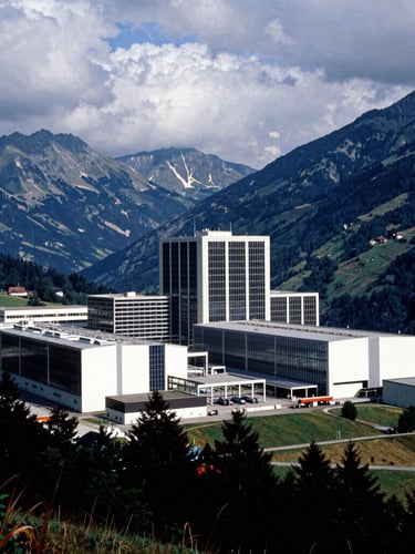 Dramatic environmental portrait of a massive clean-tech energy facility integrated into a mountainous European landscape, sharp architectural lines, high-contrast overcast daylight, medium format film.