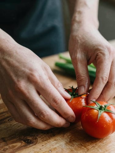 Intimate medium close-up of hands gently preparing fresh, vibrant vegetables on a rustic wooden surface, soft diffused side-light, shallow depth of field.