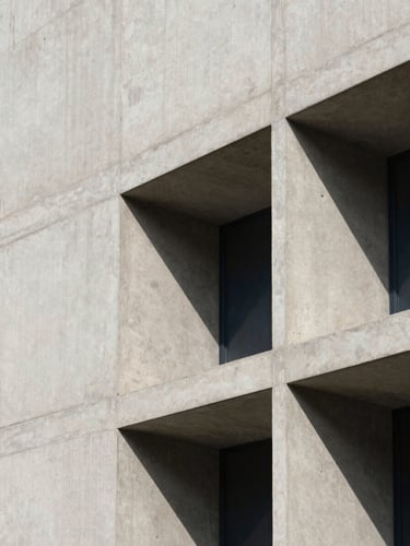 Architectural detail of a modern concrete facade with sharp shadows, soft natural daylight, minimalist structural lines, 35mm.