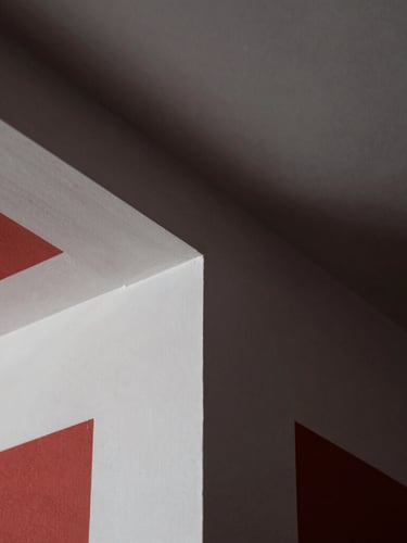 Extreme close-up of a perfectly smooth drywall corner joint, dramatic raking light highlighting clean geometric lines, white-gray plaster texture, sharp focus