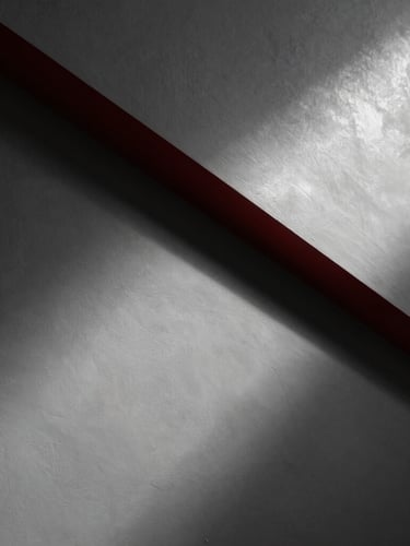 Dramatic low-angle raking light sweeping across a freshly sanded, perfectly flat plaster wall, showing ultra-smooth texture and clean geometric lines, architectural photography