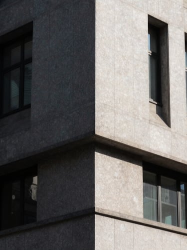 Dramatic architectural angle of a sunlit civic building facade, high-contrast shadows, clean editorial photography.