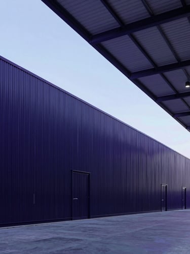 Wide-angle architectural shot of a modern clean warehouse interior in Muscat, cool-toned lighting with subtle purple and blue ambient accents, 35mm professional photography