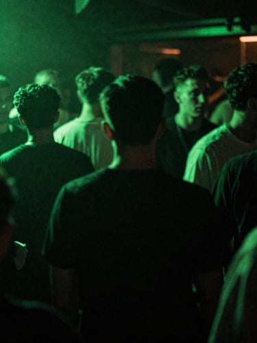 Gritty flash photography of a packed underground UK club dancefloor, high-contrast neon green ambient glow, deep shadows, 35mm film grain, motion blur.