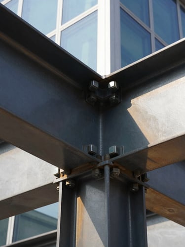Extreme close-up of a heavy structural steel beam joint secured with massive bolts, bright direct sunlight reflecting off metallic surfaces, high-contrast architectural photography