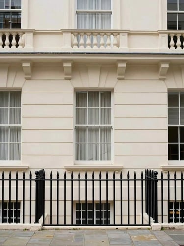 Straight-on architectural photograph of a classic cream-colored London townhouse exterior in Kensington, soft overcast daylight, elegant black iron railings, crisp details.
