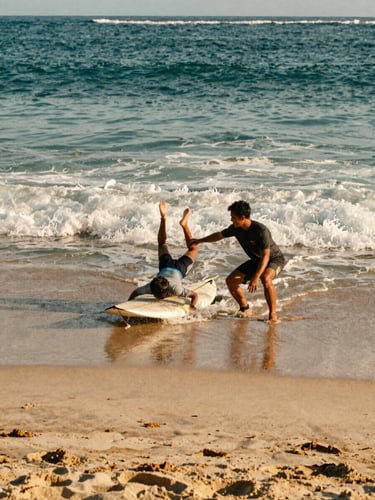 A professional surf instructor demonstrating pop-up techniques to a student on Canggu beach sand, warm golden-hour light, 35mm film style