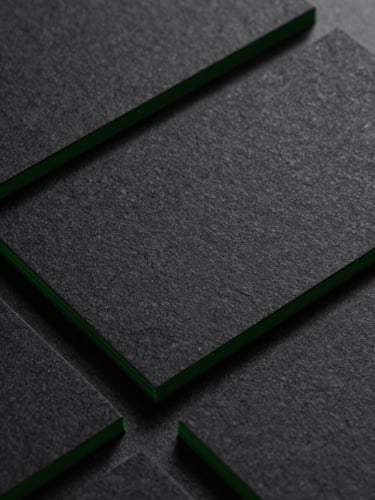 Extreme close-up of premium business cards with tech green edge-gilding, sharp directional key light casting crisp shadows on deep charcoal paper texture