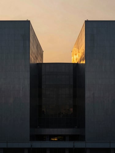 Symmetrical architectural photograph of a massive modern industrial facility in Telangana at sunset, dramatic side-lighting, amber sky reflecting on dark metallic panels