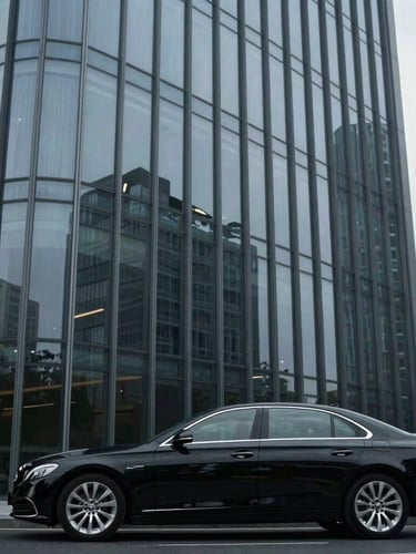 Sleek modern corporate glass skyscraper facade reflecting cool overcast sky, an executive black sedan parked cleanly in the foreground, architectural lines, 35mm