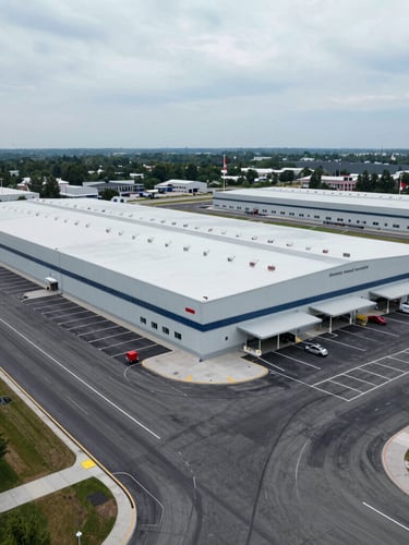 Wide-angle drone shot of a massive completed retail plaza logistics terminal in the Greater Toronto Area, freshly paved dark asphalt and sharp white line markings, overcast daylight.