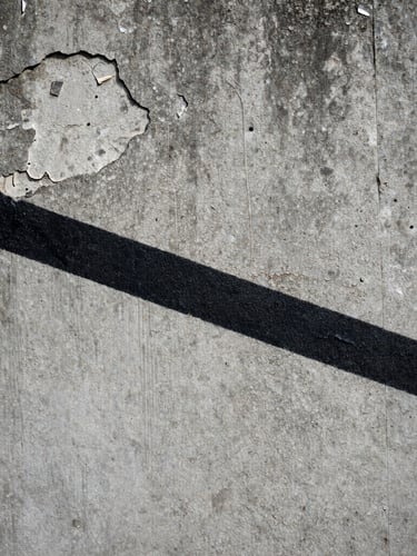 Extreme close-up of a raw, crumbling concrete wall in Chișinău, where a sharp, solid black painted line cuts across the textured decay under flat, overcast daylight.