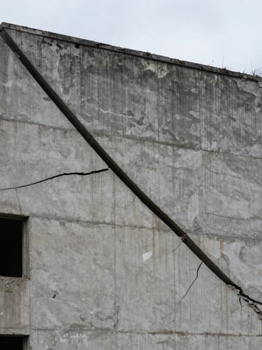 Extreme wide shot of a brutalist concrete ruin in Chisinau under overcast skies, a single sharp black line cutting across the cracked facade