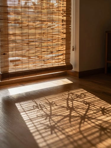 Warm afternoon sunlight filtering beautifully through a hand-woven bamboo blind onto a polished drawing room floor, creating intricate geometric shadows.