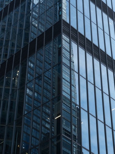 Extreme close-up of a glass skyscraper facade reflecting sharp geometric patterns and deep blue light, high contrast.