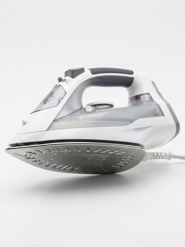 Bright high-key product photography of a heavy-soleplate electric iron on a crisp white background, clean studio lighting, sharp focus, metallic reflections, 50mm lens