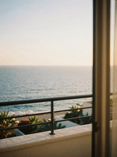 A quiet sun-drenched resort balcony overlooking the Mediterranean sea, warm golden hour light, soft 35mm film texture, shallow depth of field.