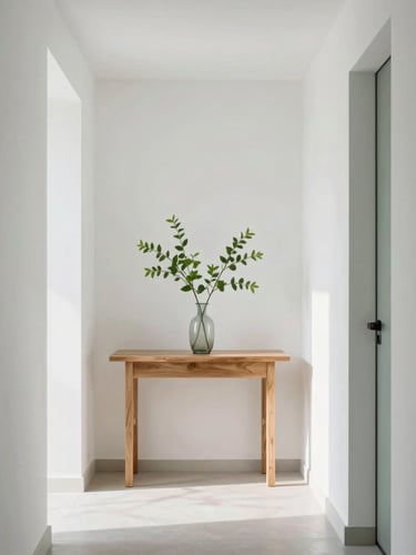 A bright, airy hallway with clean architectural lines, a simple wooden console table holding a vase of fresh green leaves, soft natural daylight, 35mm editorial photography