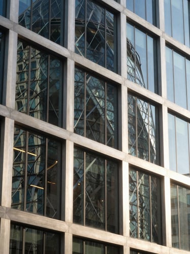 Crisp architectural photography of a modern financial center facade in London, sharp geometric steel and glass lines reflecting bright natural daylight, cool blue and warm champagne highlights, 35mm lens, sharp focus