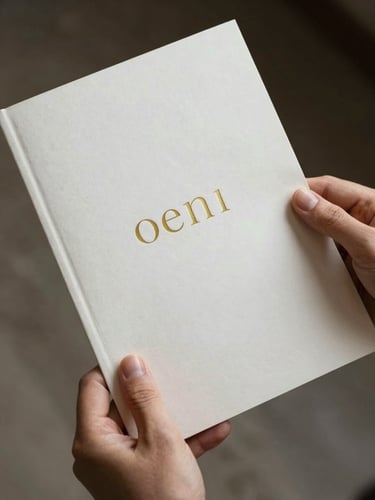 Hands holding a beautifully printed, thick cotton paper manual with minimalist gold typography, soft natural side lighting.