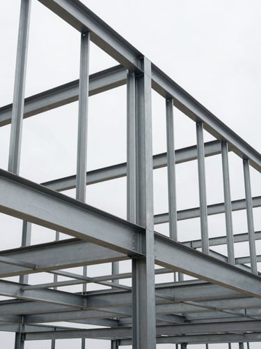 Low-angle architectural shot of a light gauge steel frame structure under high-contrast daylight, showing precise vertical and horizontal studs and tracks