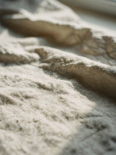 Macro detail of aged raw linen fabric showing soft wrinkles and heavy-weight weave, warm afternoon sun casting soft shadows, 35mm film