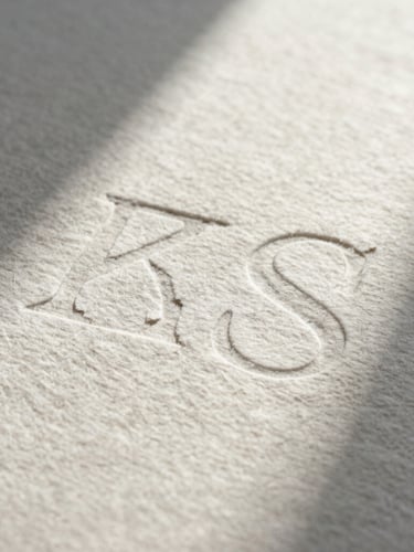 A close-up of heavy cotton paper stock with debossed typography, soft afternoon shadows casting across the textured surface.