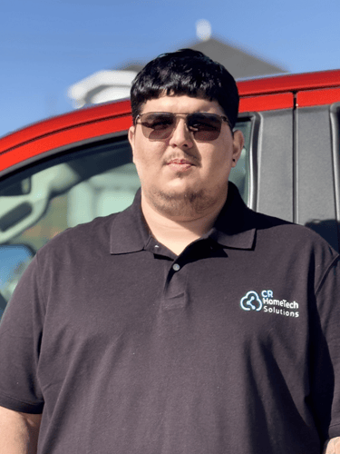 CR HomeTech Solutions technician in a black polo shirt standing in front of a red service vehicle.