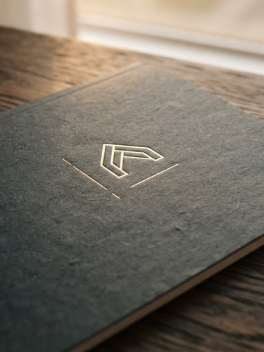 Close-up of a premium, textured paper report cover with subtle gold foil lettering, resting on a dark wood surface, soft diffused light, editorial style.