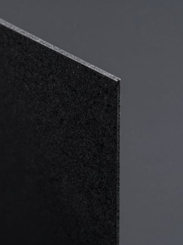 Extreme macro close-up of a heavy-gauge dark obsidian paper edge, sharp raking light from the side revealing rich tactile texture, deep shadows, minimalist architectural feel.