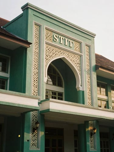 Portrait orientation of the historic main building of STIT Bandung, featuring traditional Islamic geometric details in soft morning light, deep emerald and gold tones, shallow depth of field, 35mm.